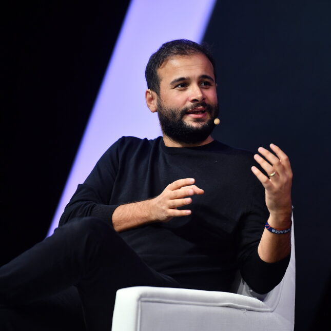 a photo of eren bali wearing a black shirt and speaking on a stage