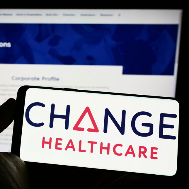 A phone screen displays Change Healthcare's logo in front of a laptop screen that shows the company's website — business coverage from STAT