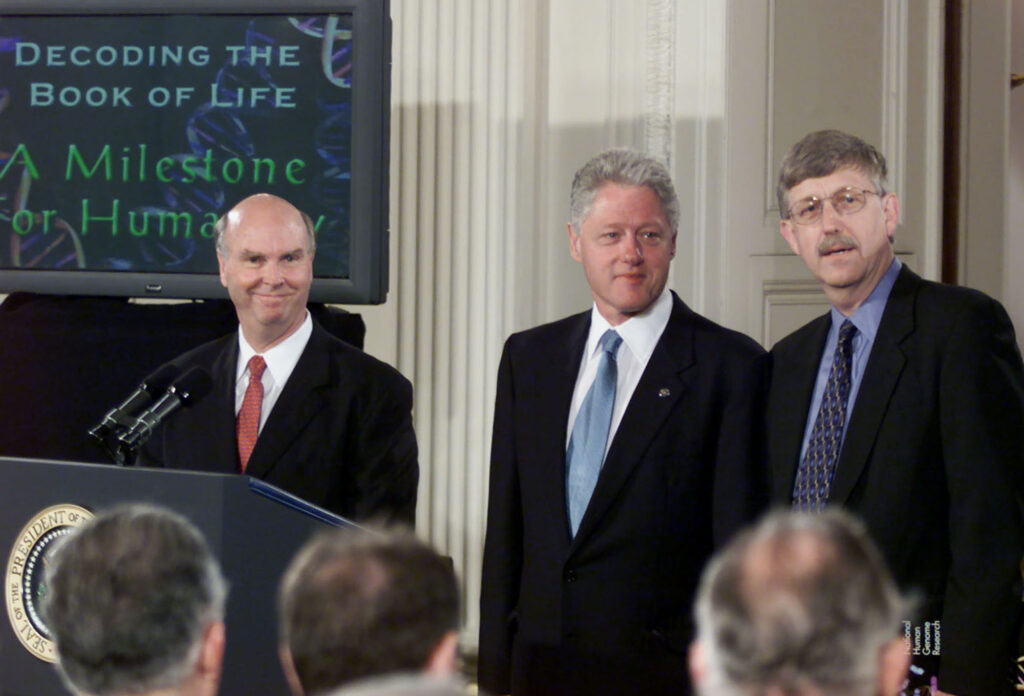 President Bill Clinton, J Craig Venter (L) and Dr. Francis Collins of the National Institute of Health look at the audiance during an in the East Room of the White House, June 26, 2000.